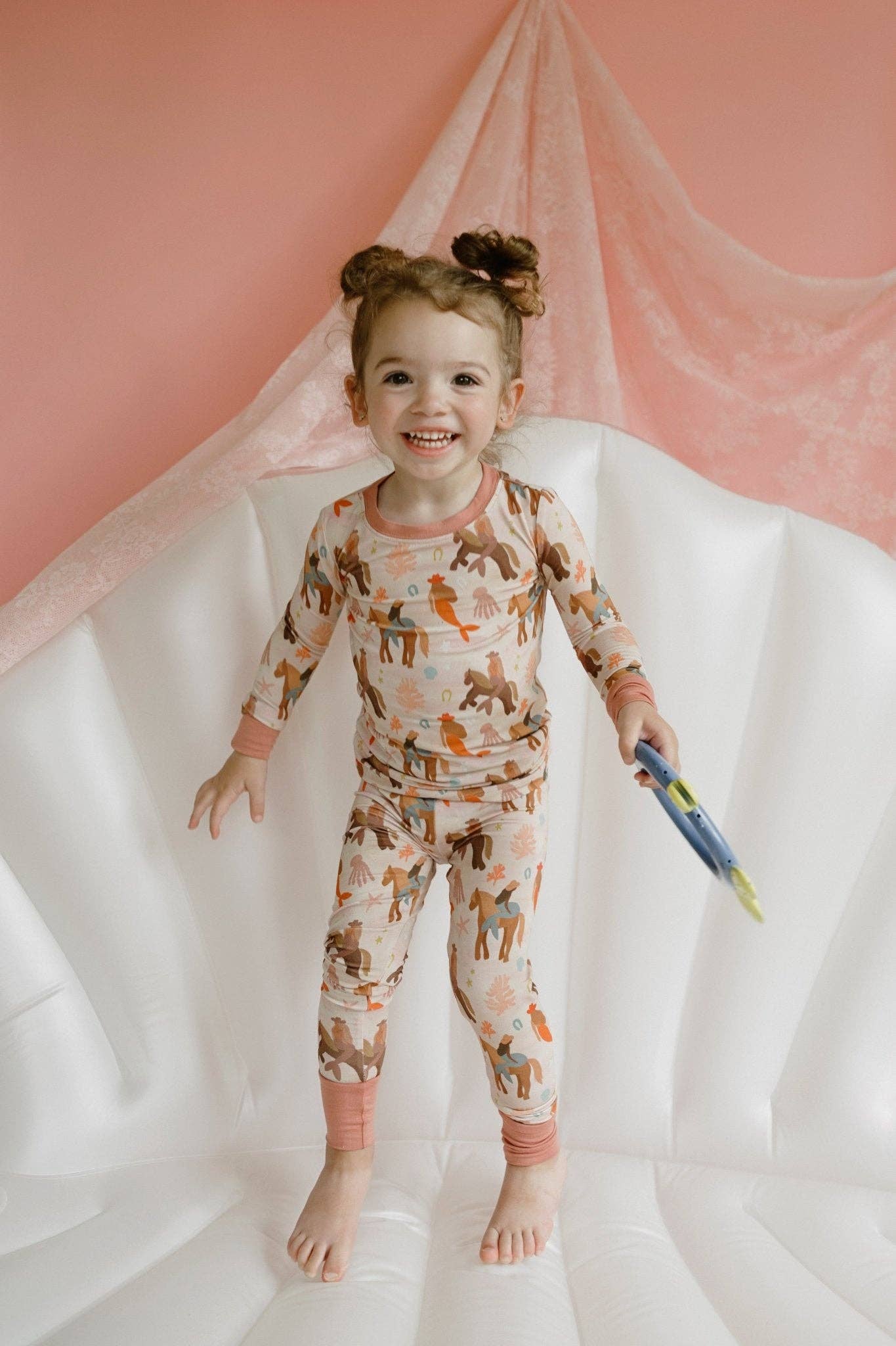 Child wearing patterned pajamas with a pink and white background