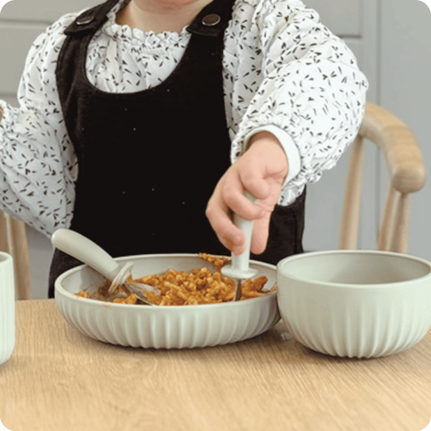 Person in a kitchen setting with a bowl of food and a spoon.