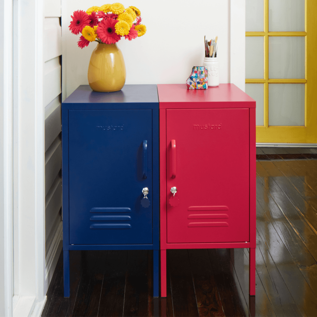 Colorful locker-style cabinet with a vase of flowers on top, against a white wall.