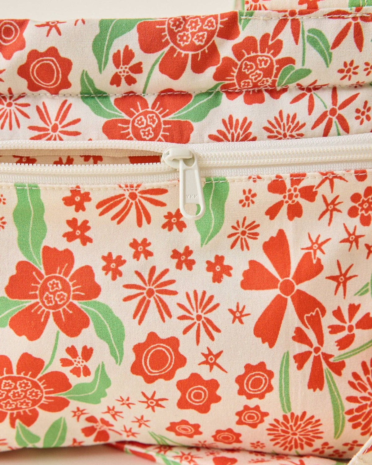 Floral-patterned fabric with red and green flowers on a beige background
