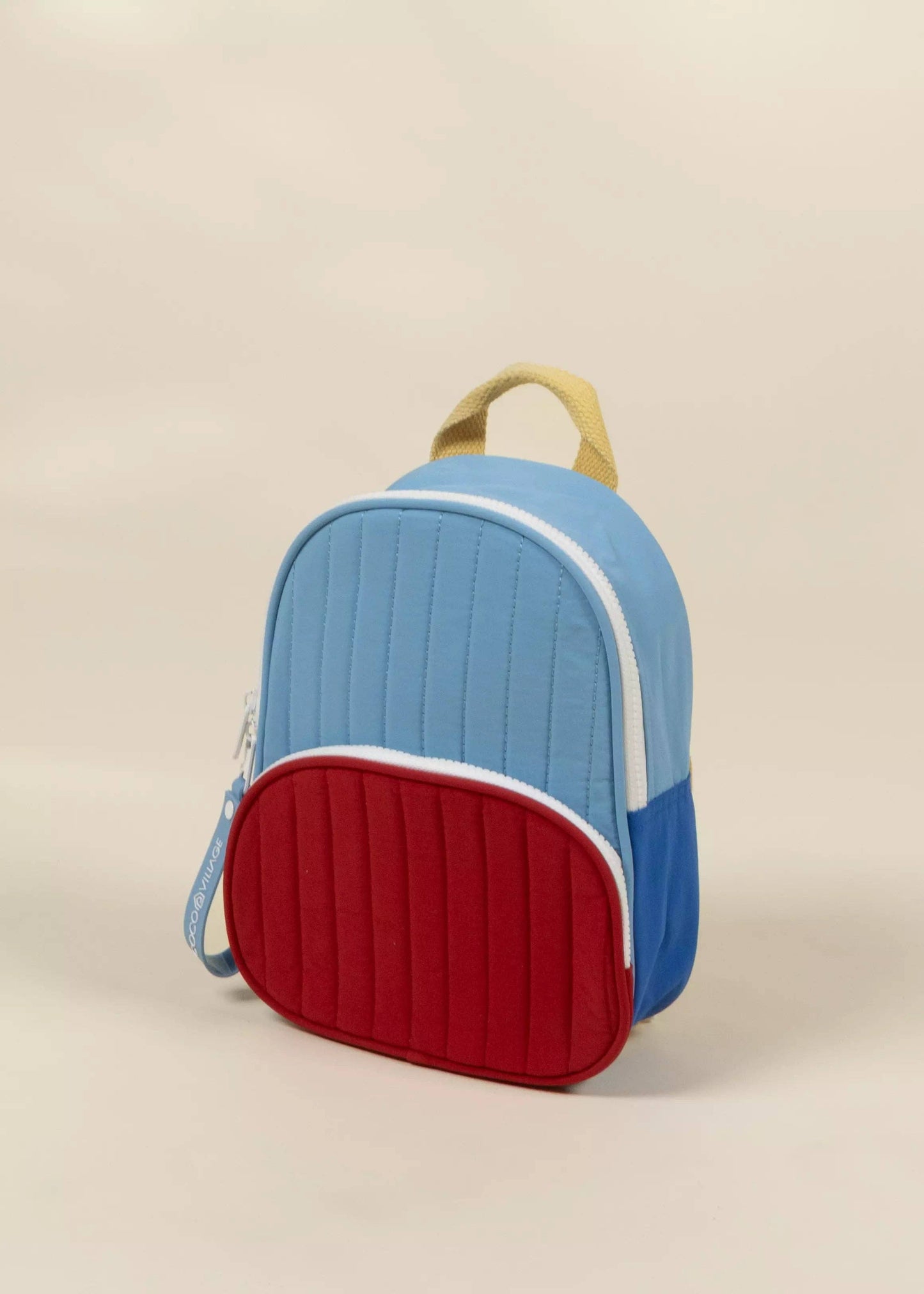Children's backpack with blue top and red bottom on a beige background