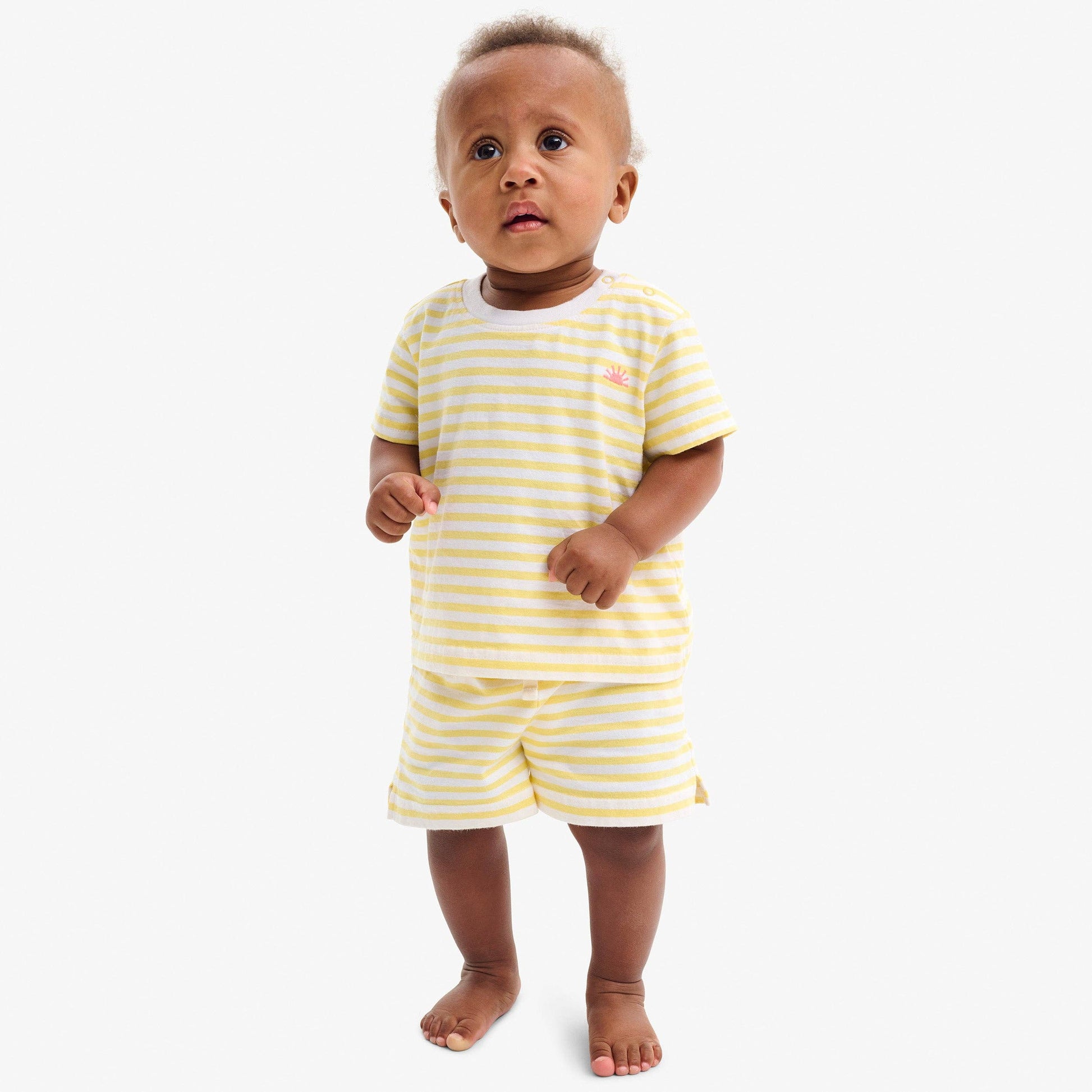Baby wearing a yellow and white striped outfit on a white background