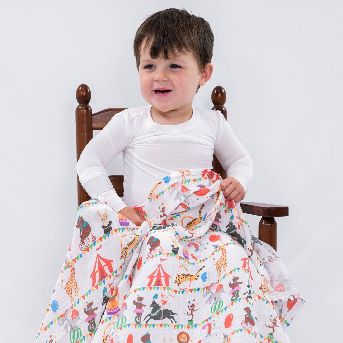 Child sitting on a chair with a colorful animal-patterned blanket