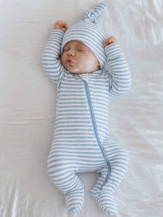 Newborn baby in a blue and white striped outfit lying on a white surface