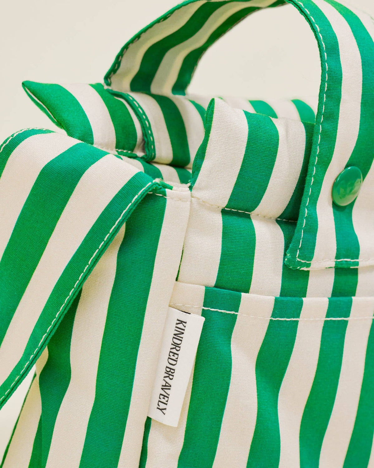 Green and white striped stroller bag with a brand label on a beige background