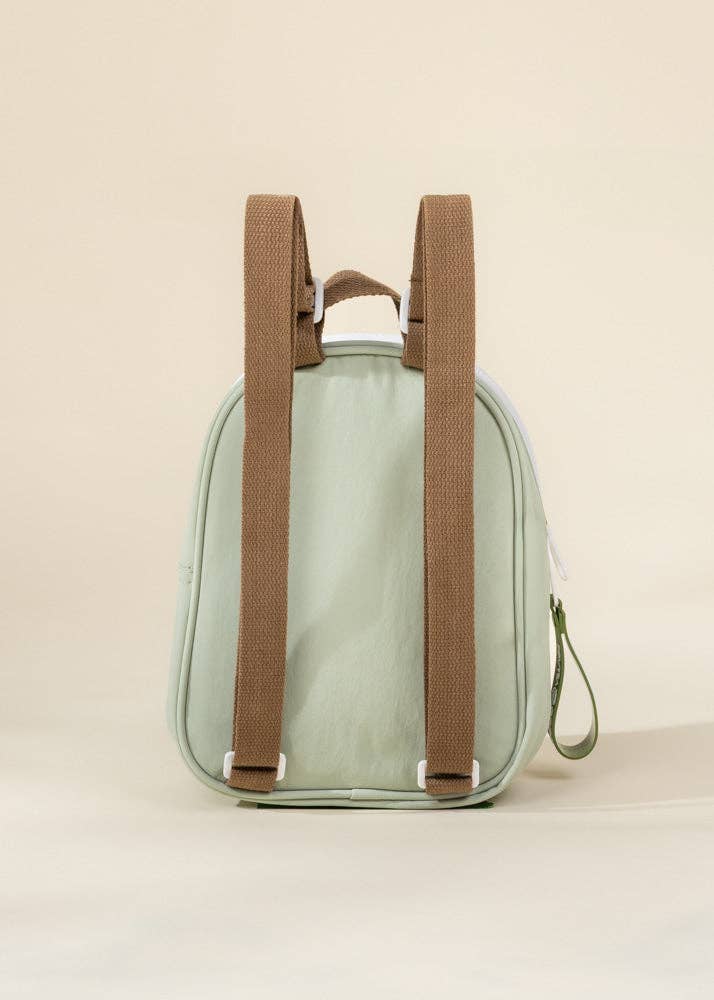 Small green backpack with brown straps on a beige background