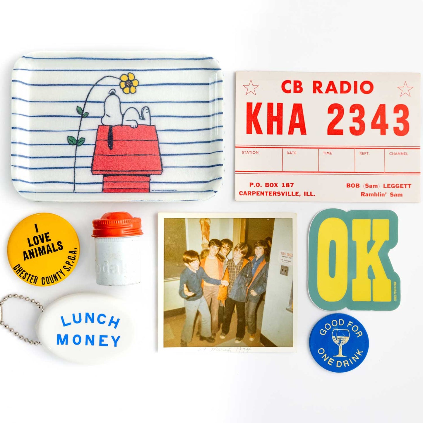 Collection of vintage-style items including a Snoopy lunchbox, CB radio station sign, and 'Lunch Money' container on a white background.