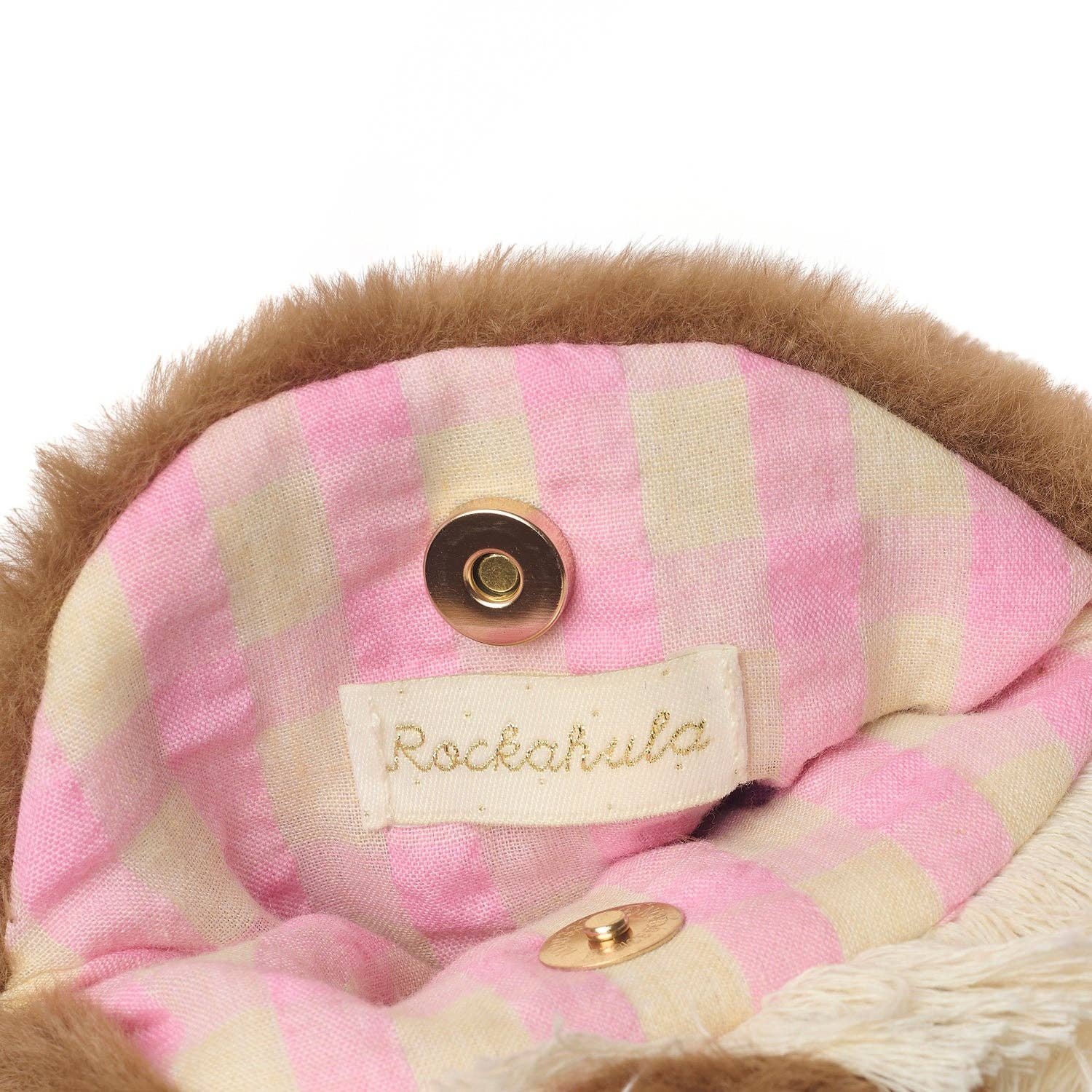 Close-up of a pink and cream checkered fabric interior with a brown faux-fur trim, a RockaRula brand label, and gold-tone snap buttons.