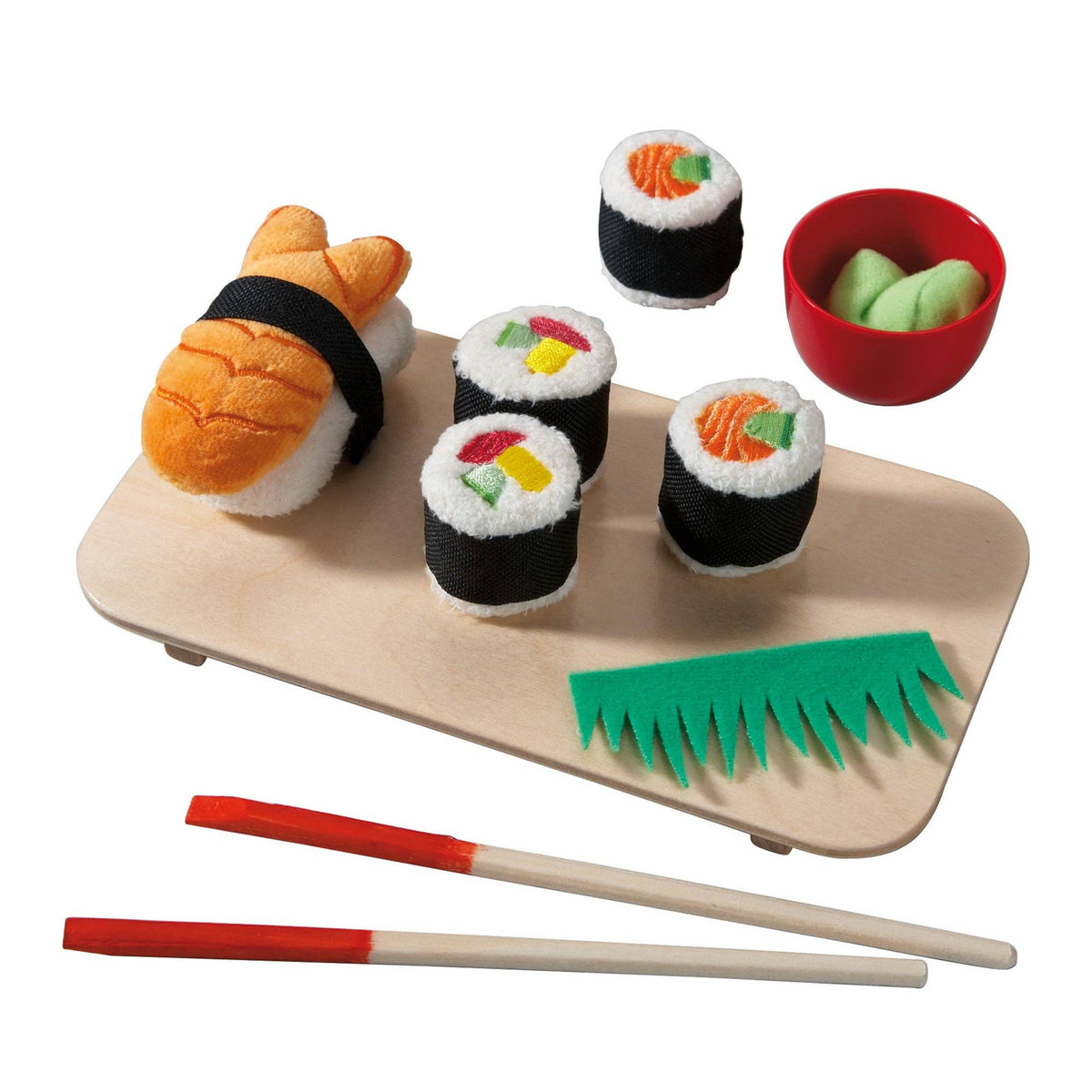 A plush toy sushi set arranged on a light wood tray, including a large orange fish nigiri, three black-and-white maki rolls with colorful fillings, a small red bowl with green wasabi, and two chopsticks with red handles, all photographed on a white background.