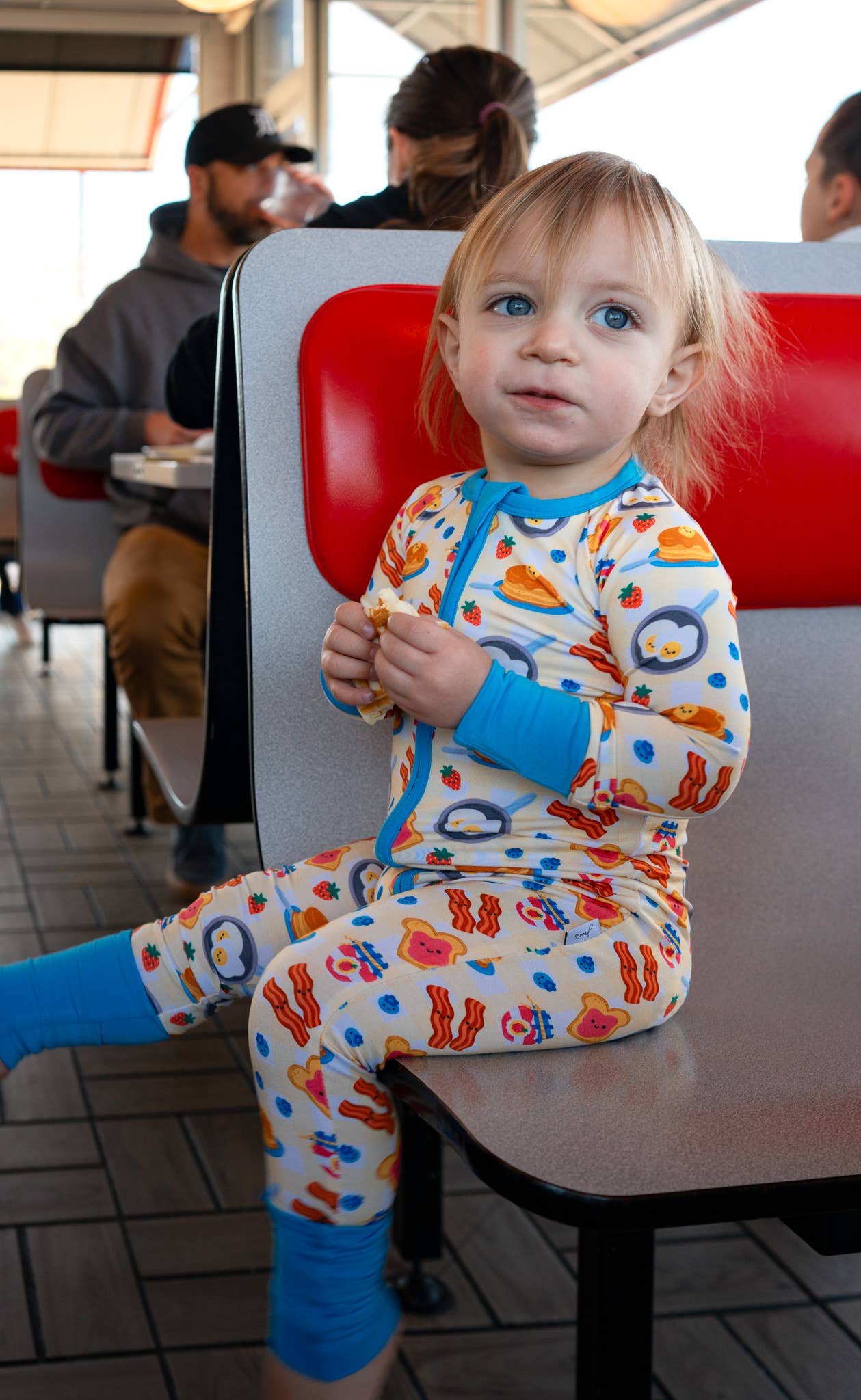 Child in colorful pajamas sitting at a table in a casual setting