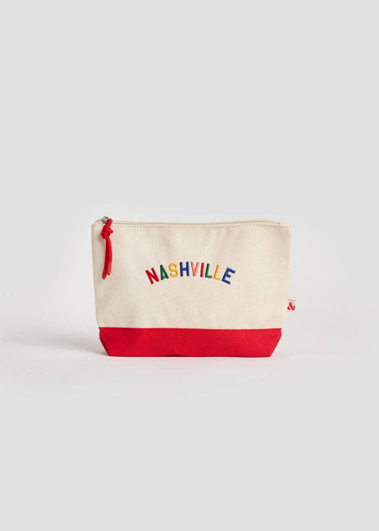 An off-white canvas zippered pouch with a solid red bottom panel and 'NASHVILLE' embroidered in multicolored letters across the front, set against a light gray background.