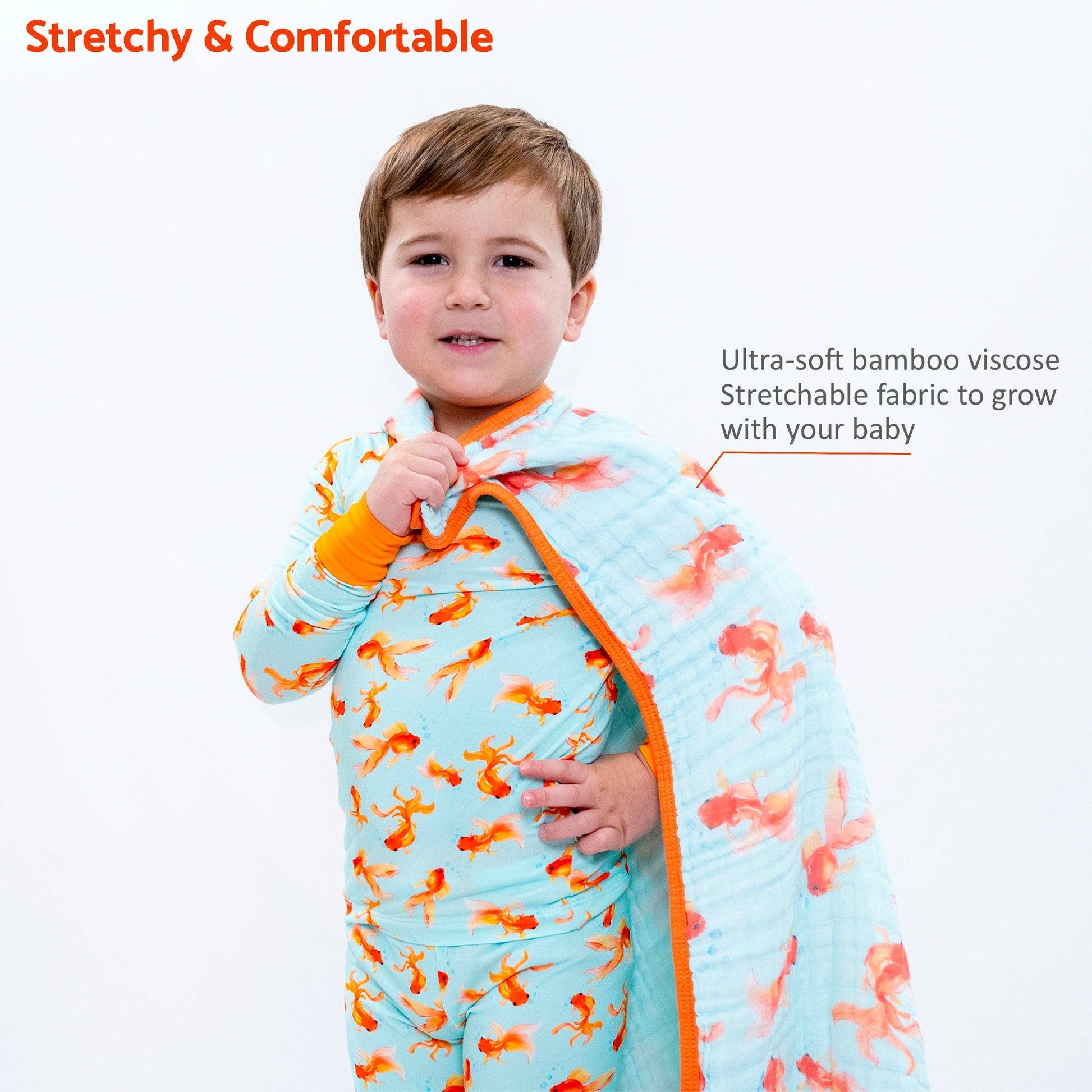 Child wearing a colorful baby quilt with goldfish pattern, text about stretchy and comfortable fabric.