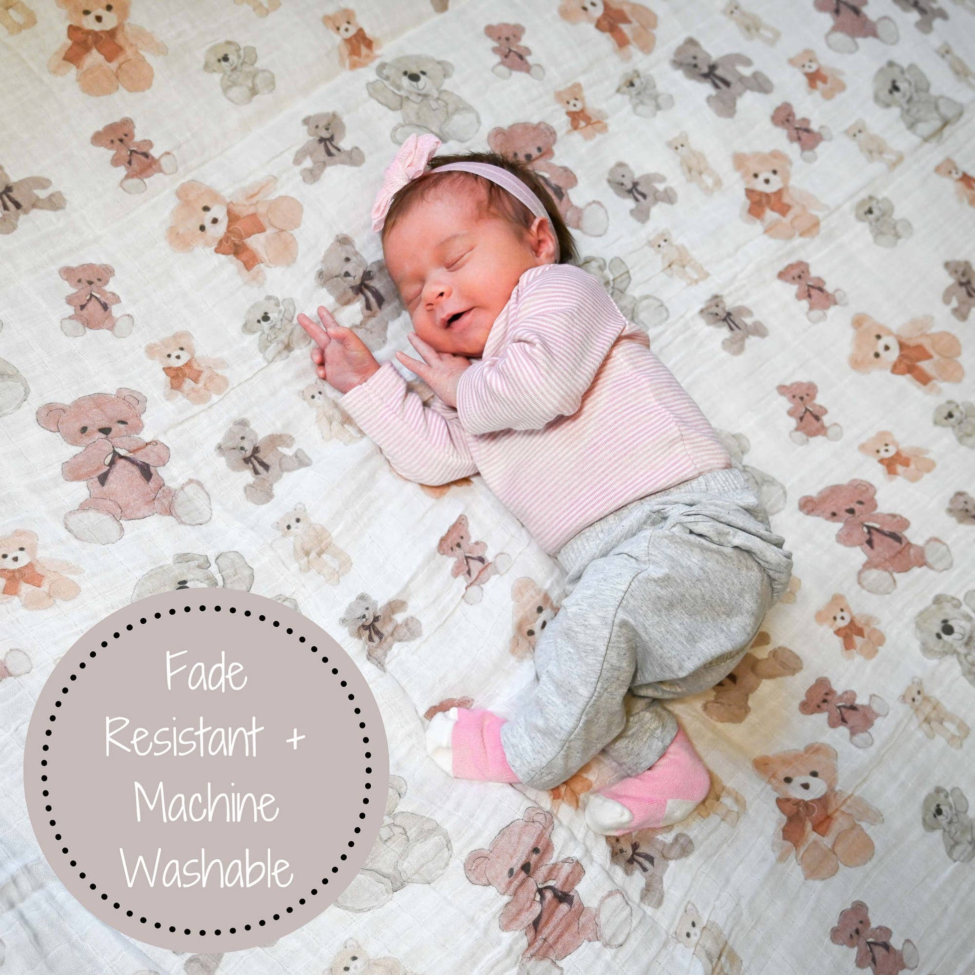Newborn baby sleeping on a blanket with teddy bear pattern, wearing pink and gray outfit.