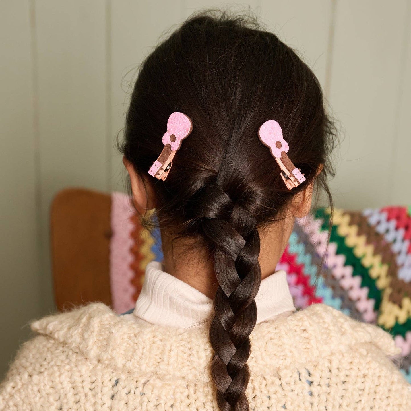 Person with braided hair wearing pink hair clips in a home setting