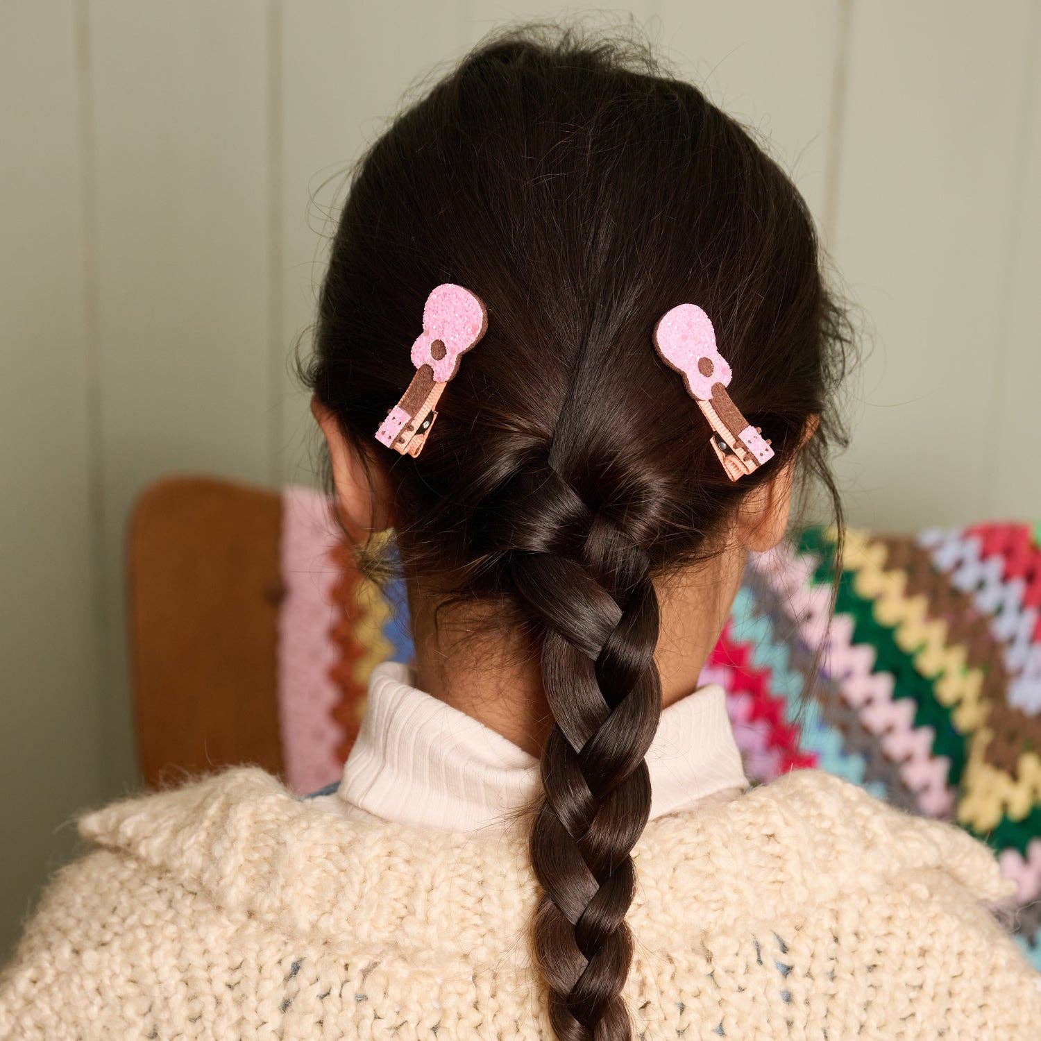 Person with braided hair wearing pink hair clips in a home setting