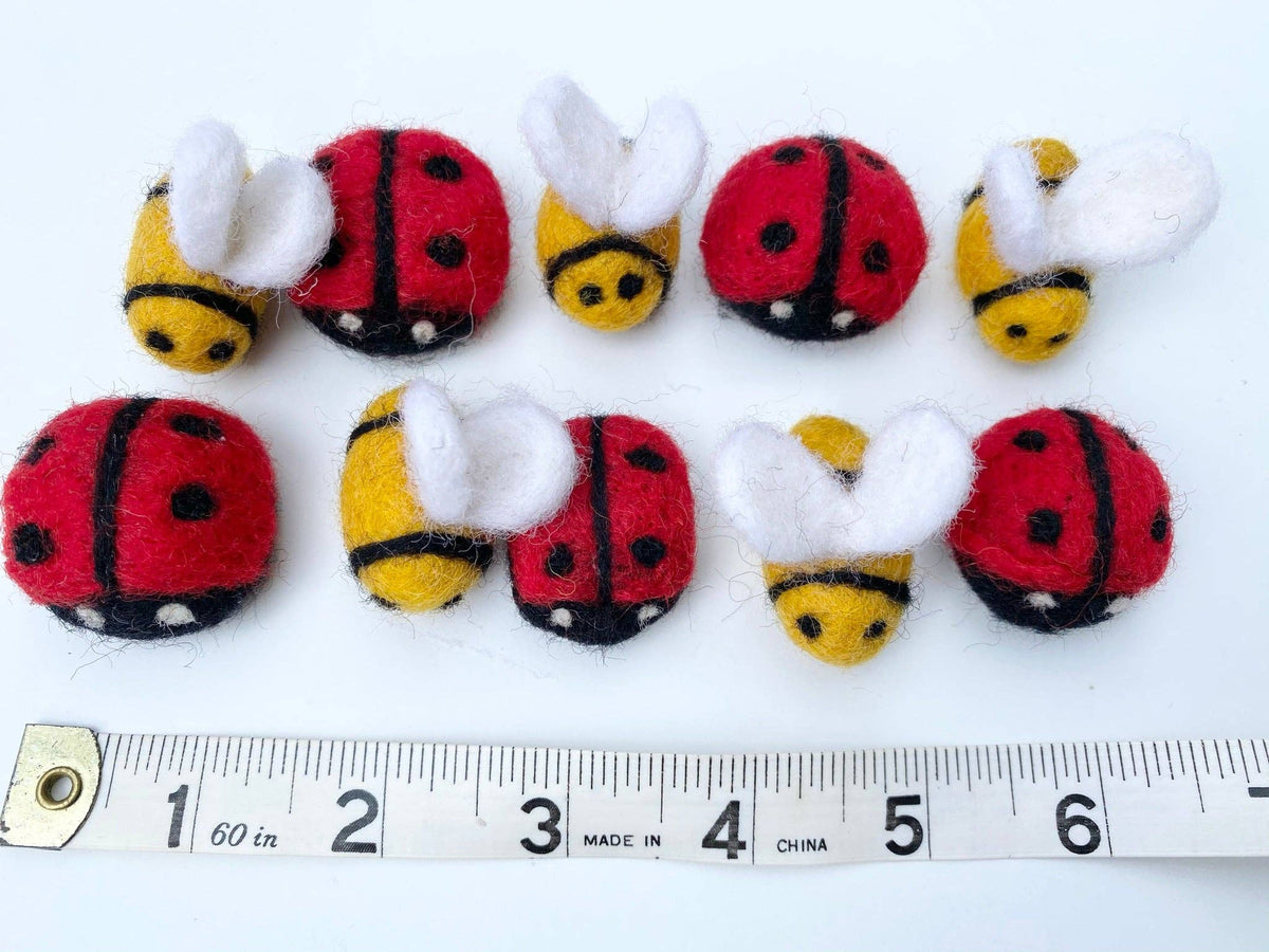 Set of ladybug and bee-shaped toys with a ruler for scale on a white background