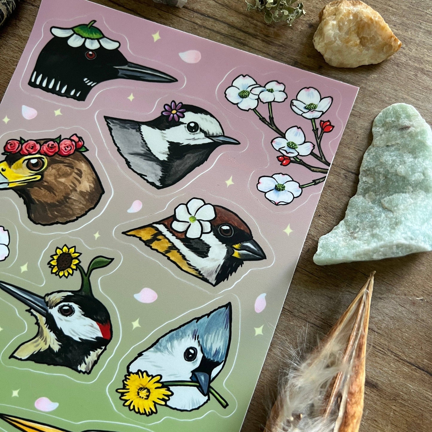 Sheet of bird stickers with a pink and green background on a wooden surface.