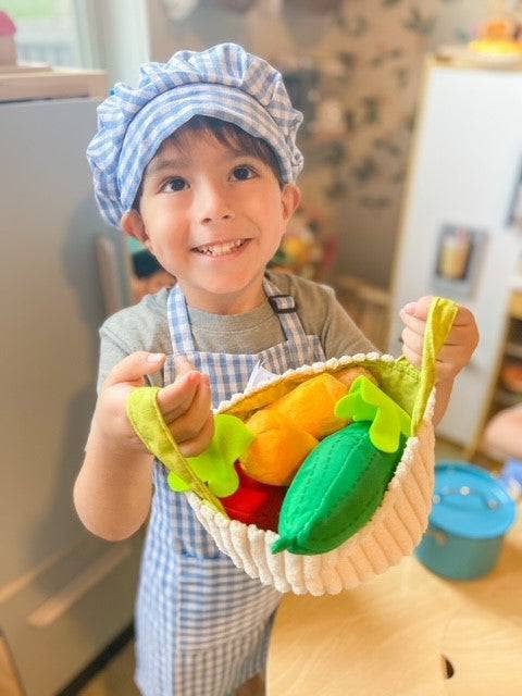 Child holding a toy vegetable basket in a kitchen