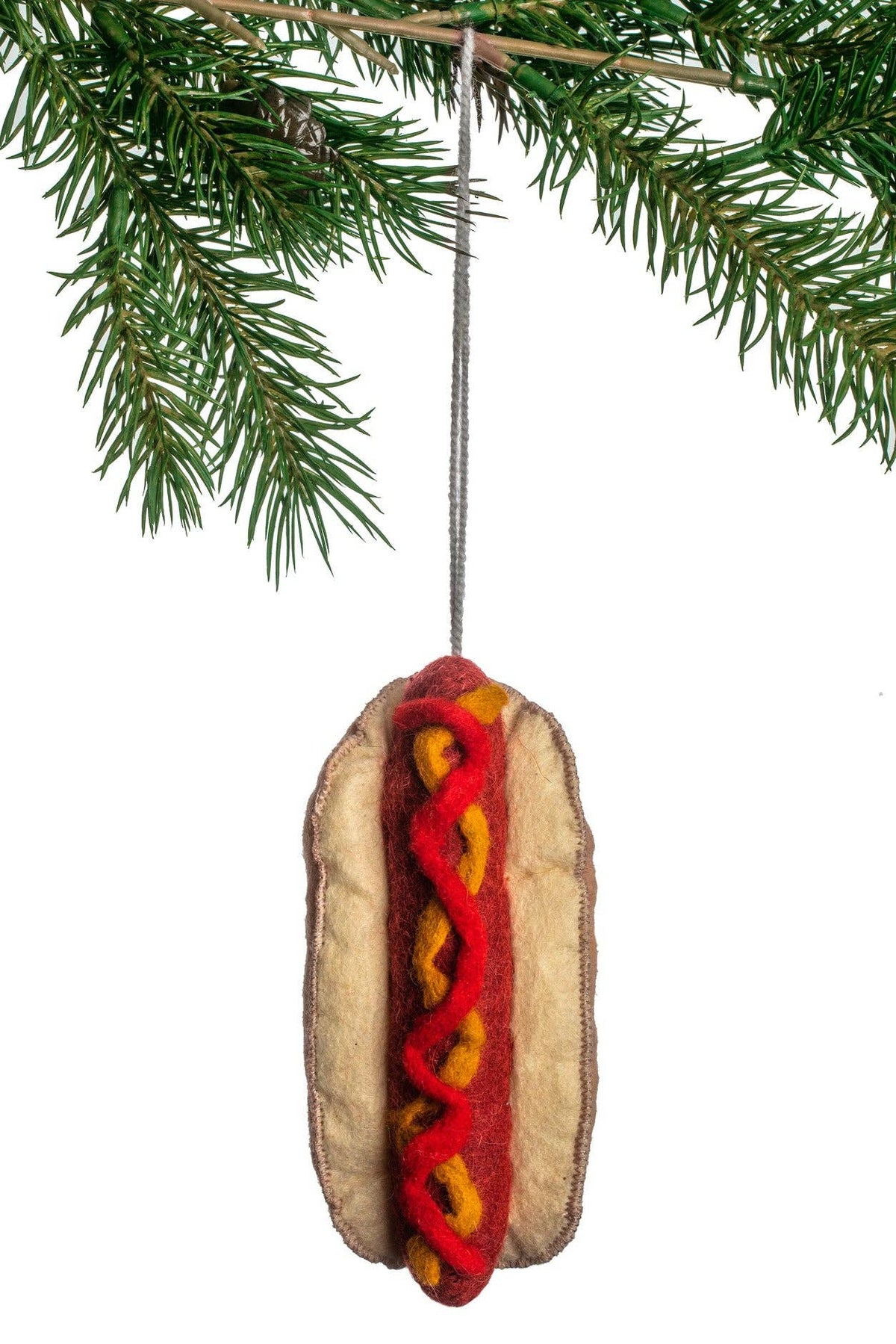 Hot dog ornament hanging from a pine branch on a white background