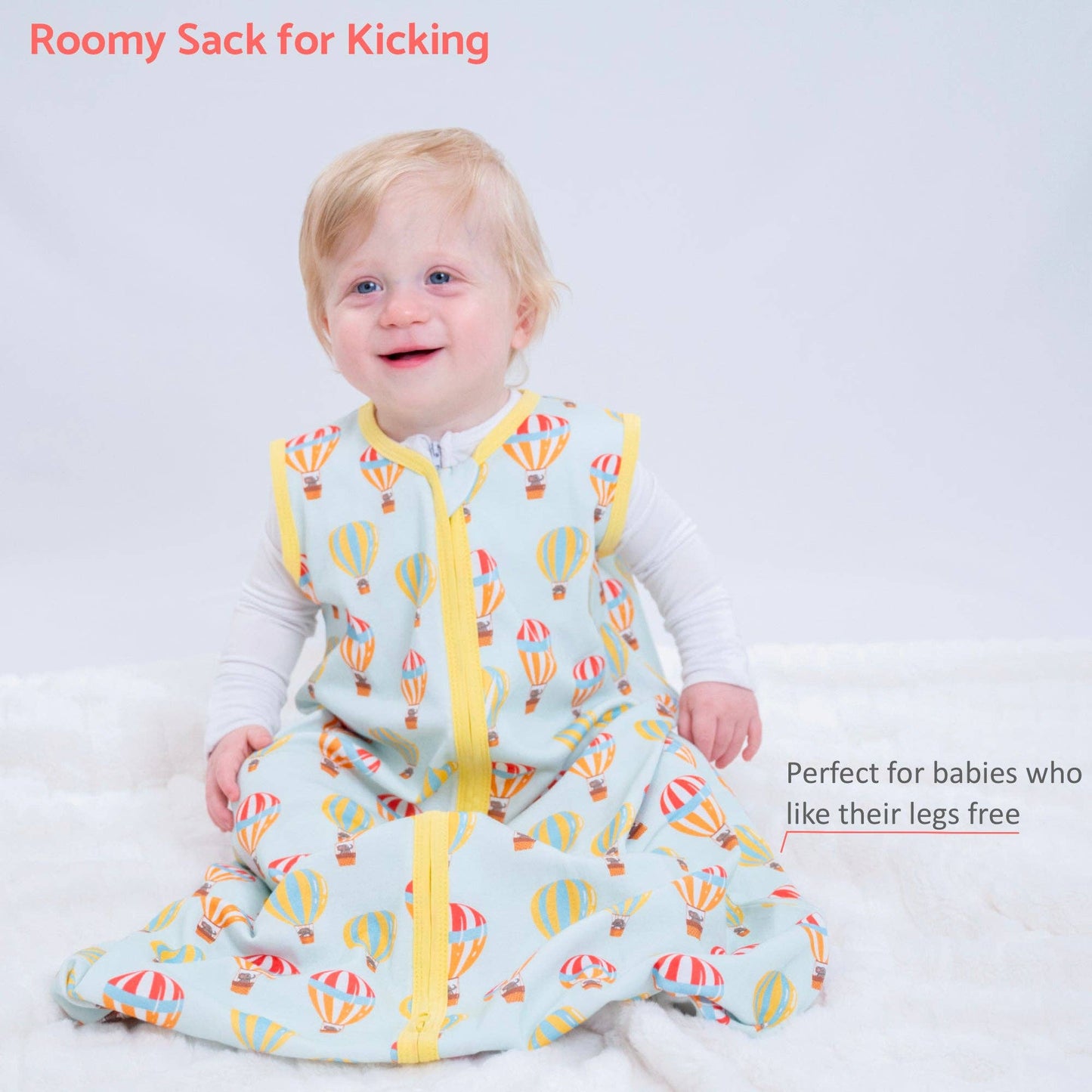 Baby in a colorful roomy sack with hot air balloon pattern on a white background