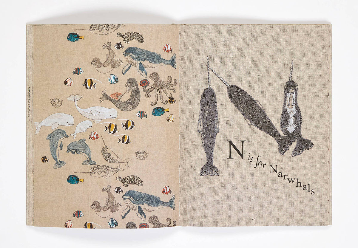 Book with illustrations of narwhals and other sea creatures on a beige background