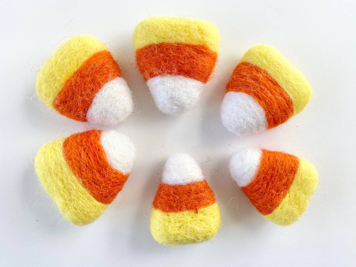 Six hand-felted candy corn toys arranged in a circle on a plain white background.