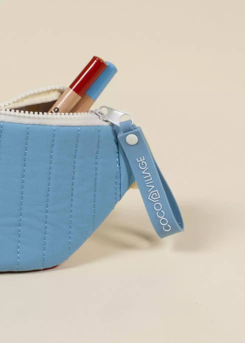 Blue pouch with a red lip balm on a beige background