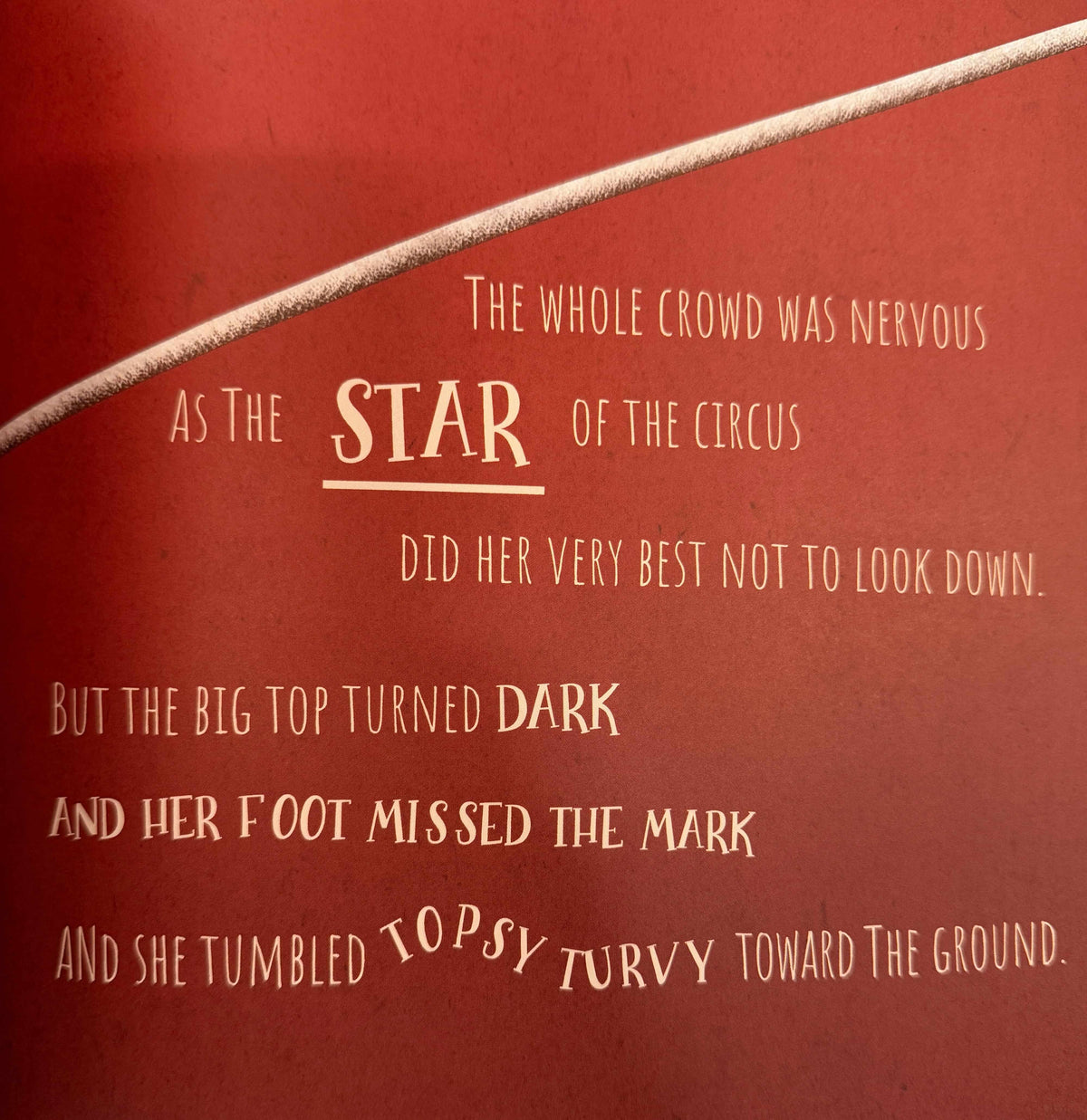 A close-up of a red book cover featuring cream-colored text from 'The Little Prince' and a diagonal beige cord or string across the top.
