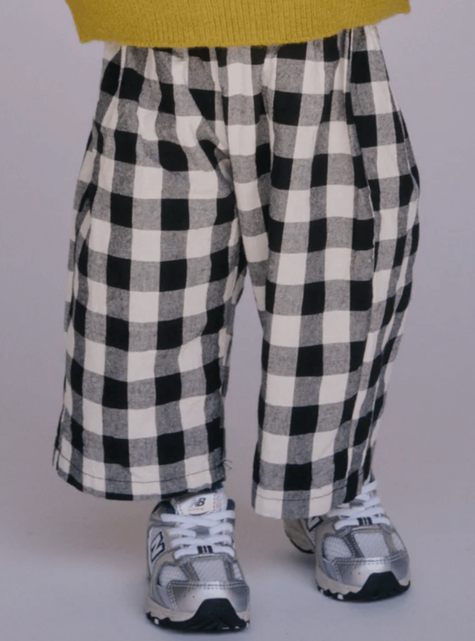 Black and white checkered pants worn by a person on a plain background