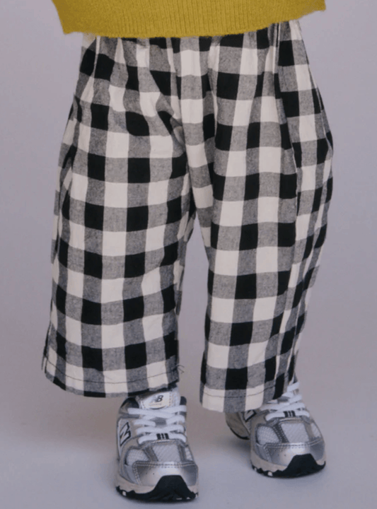 Black and white checkered pants worn by a person on a plain background