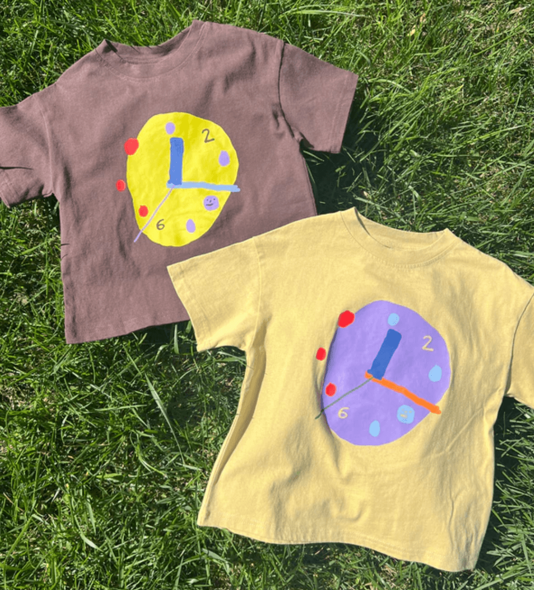 Two t-shirts with clock designs on a grass background