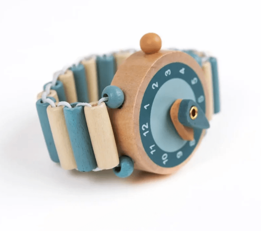 A wooden toy watch with a natural wood body, a blue and beige segmented band, and a blue dial with white numbers, shown on a white background.
