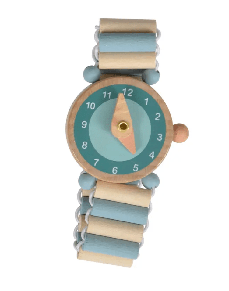 A wooden toy watch with a light blue and beige beaded strap, a round wooden case, and a light blue dial with white numbers and a peach-colored hour hand.