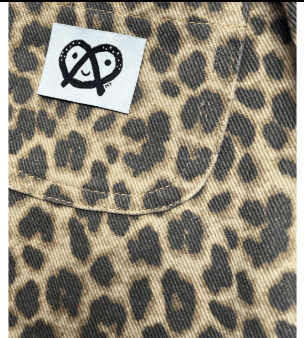 Close-up of a leopard print fabric product with a white brand patch featuring a black pretzel logo.