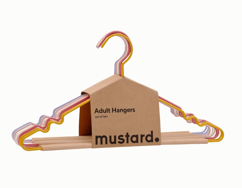 Mustard brand adult hangers set in a cardboard house-shaped packaging box, featuring natural wood bases with pastel pink, yellow, and blue wavy metal wire hanger arms, shown on a white background.