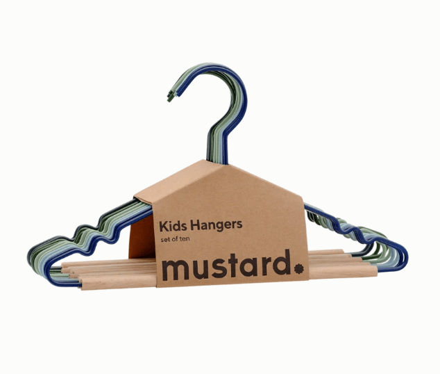 A set of mustard brand kids hangers made from metal and natural wood, packaged with a cardboard house-shaped sleeve that features the mustard logo. The hangers have wavy, striped metal supports in shades of blue, green, and gray, and are shown against a plain white background.