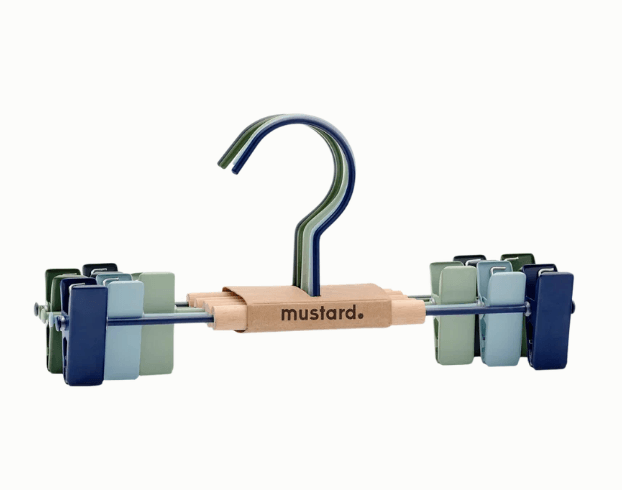 Metal pants hanger with a natural wood center bar engraved with the brand name 'mustard.' and a blue metal hook.