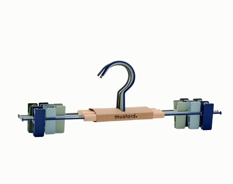 A mustard-branded multi-piece hanger set featuring a wooden central bar, a blue metal hook, and multiple small plastic clips in blue, green, and gray, shown on a plain white background.