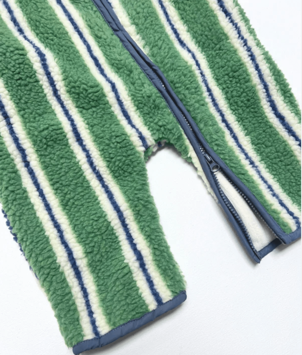 Close-up of a fleece zip-up garment with vertical green, white, and navy stripes, showing the soft textured fabric and zipper details on a white background.