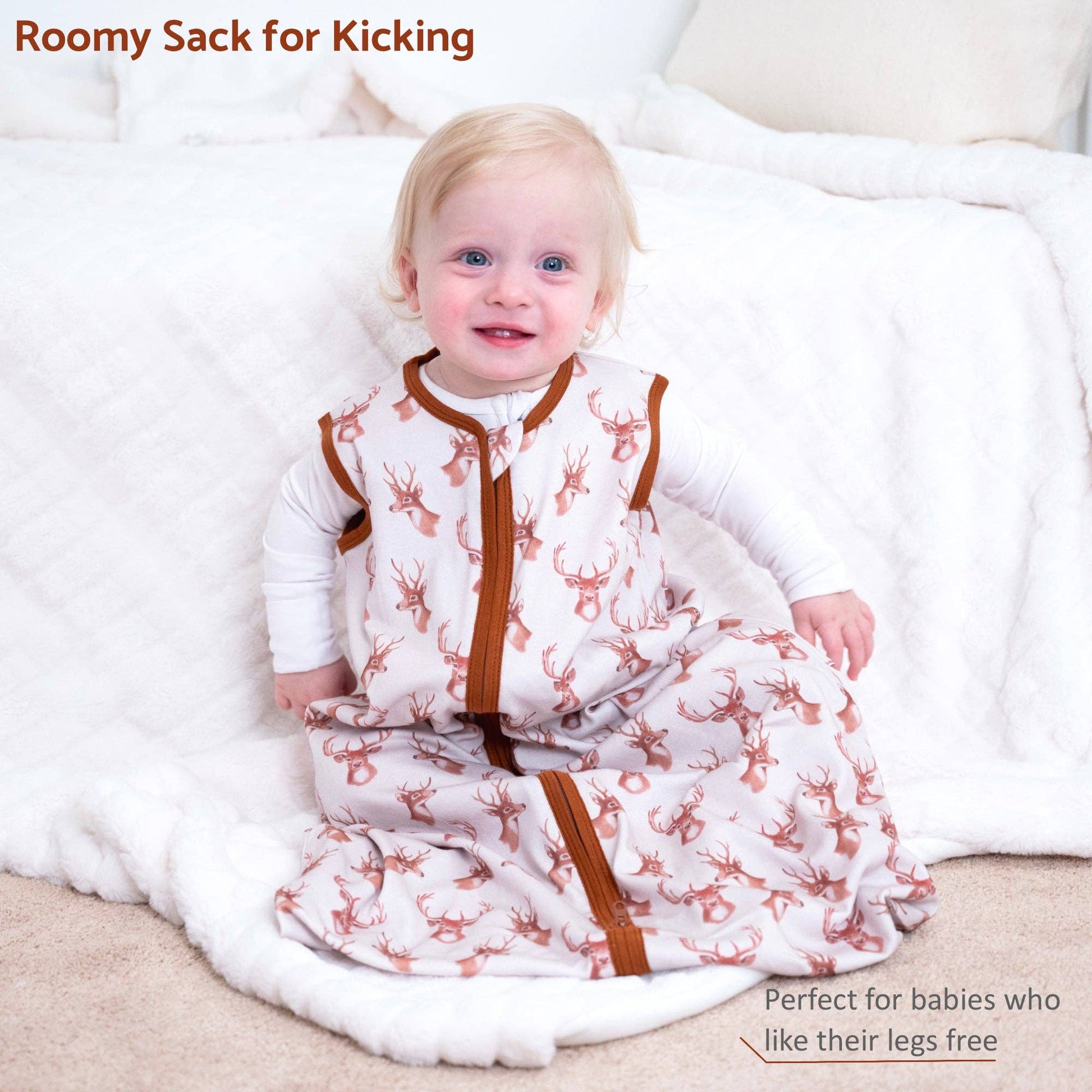 Baby in a roomy sack with deer pattern sitting on a white surface.