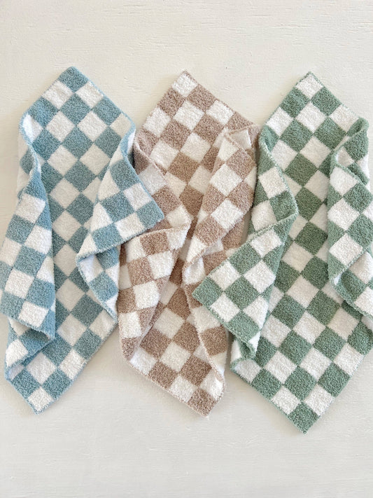 Three checkered baby lap blankets in blue, brown, and green on a light background