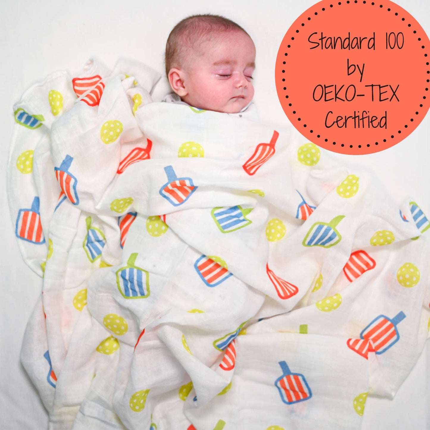 Baby wrapped in a colorful blanket with OEKO-TEX certification label