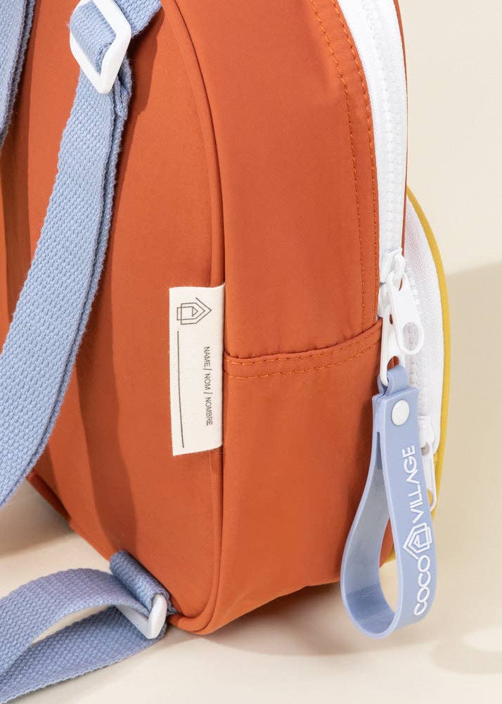 Orange bag with blue strap and keychain on a beige background