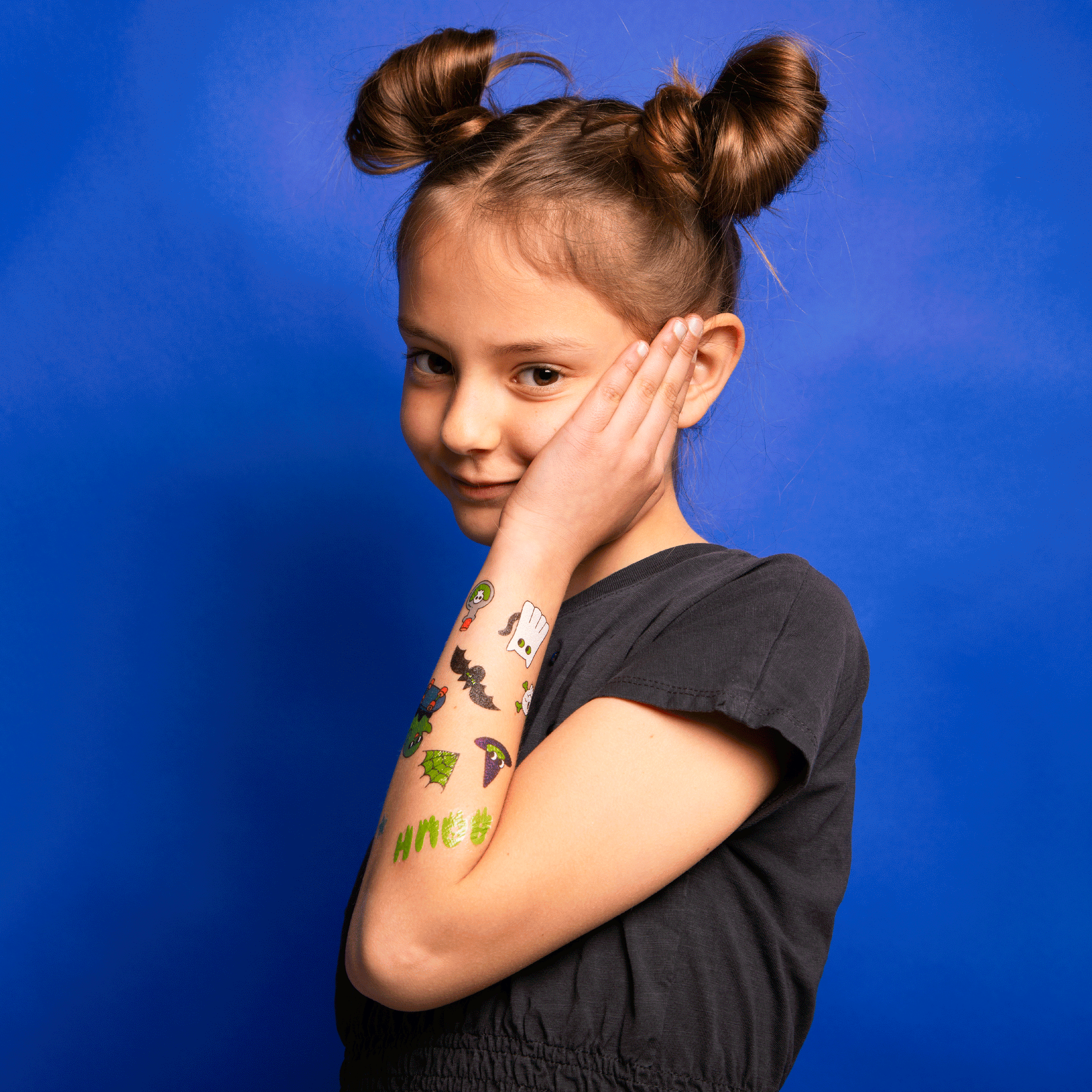 Flashing video of child with temporary tattoos glowing in the dark on their arm against a blue background.