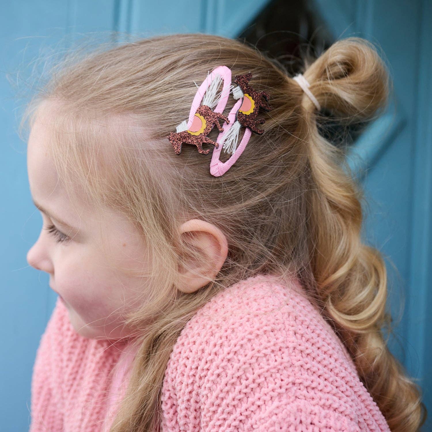 Child with a decorative hair clip in their hair against a blue background