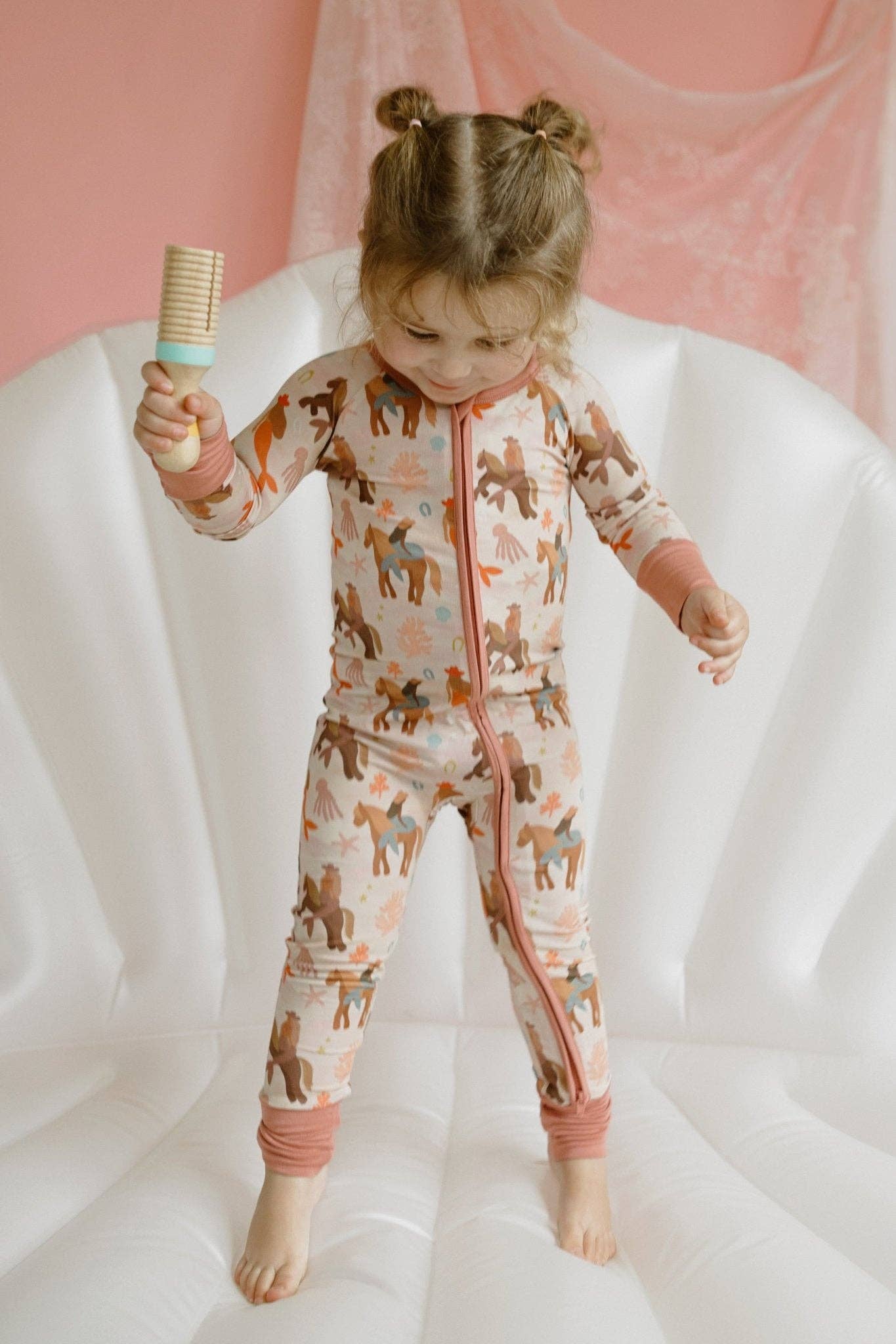 Child wearing a patterned outfit with a pink and white background