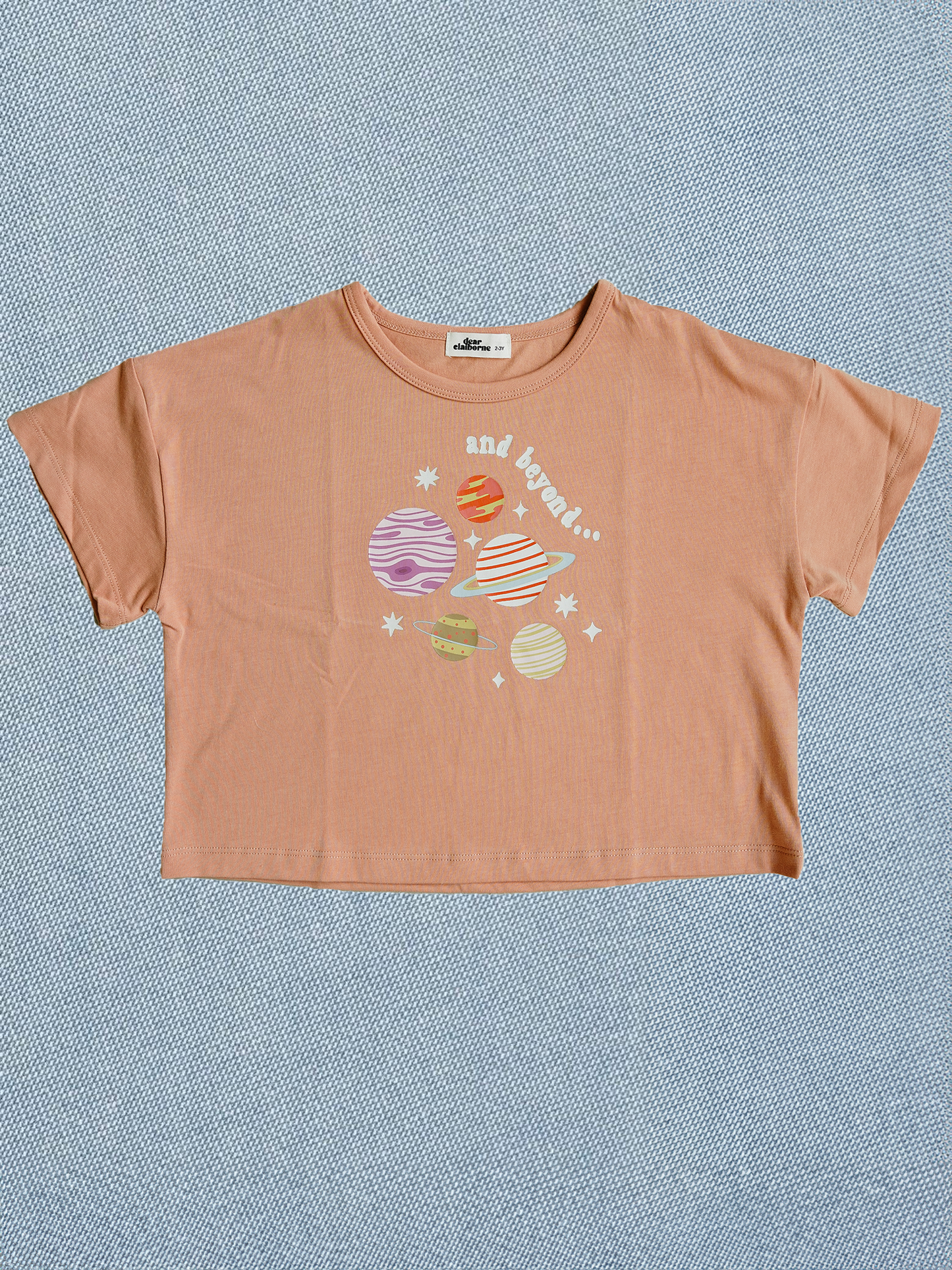 Orange t-shirt with space-themed graphic on a blue textured background