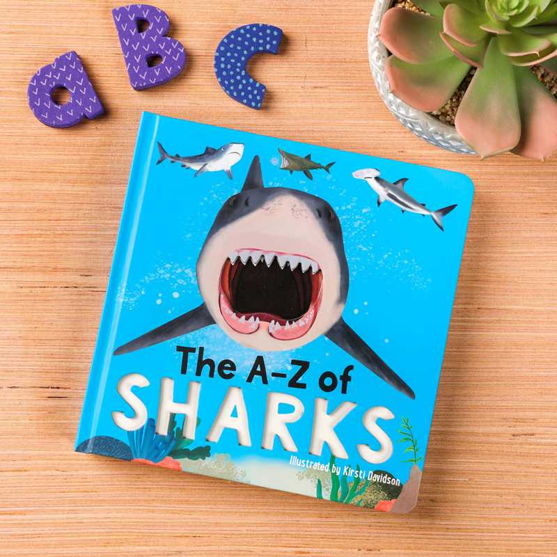 Children's book titled 'The A-Z of Sharks' on a wooden surface with shark illustrations and educational letters.