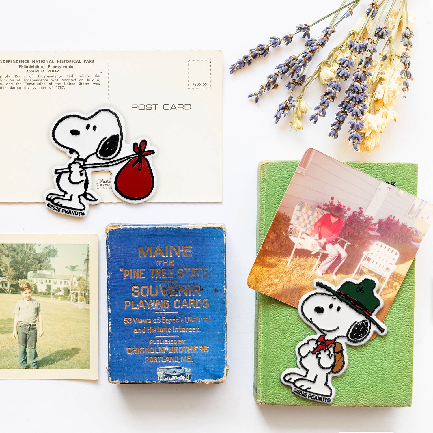 Collection of vintage items including a postcard, playing cards, and a book with Snoopy illustrations on a white background.