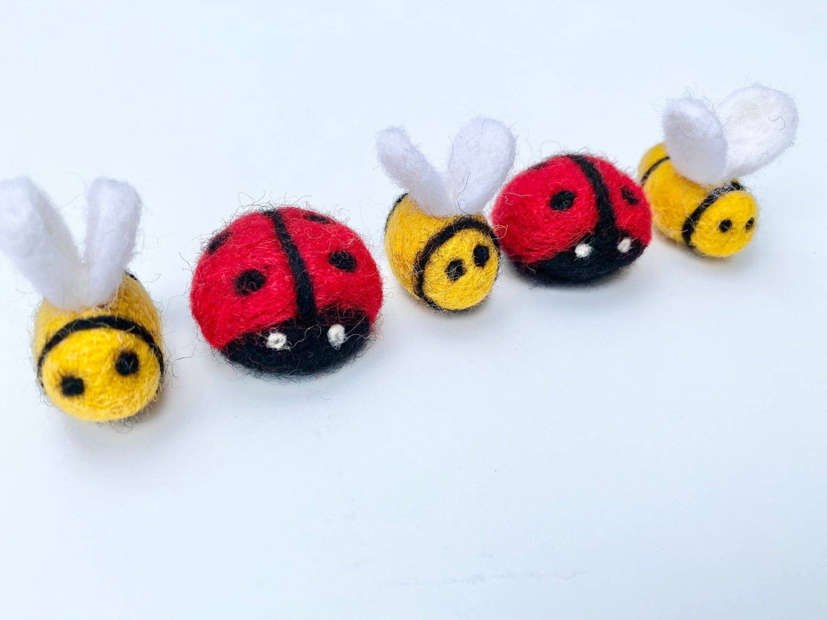 Five small toy figures resembling ladybugs, bees, and a worm on a white background
